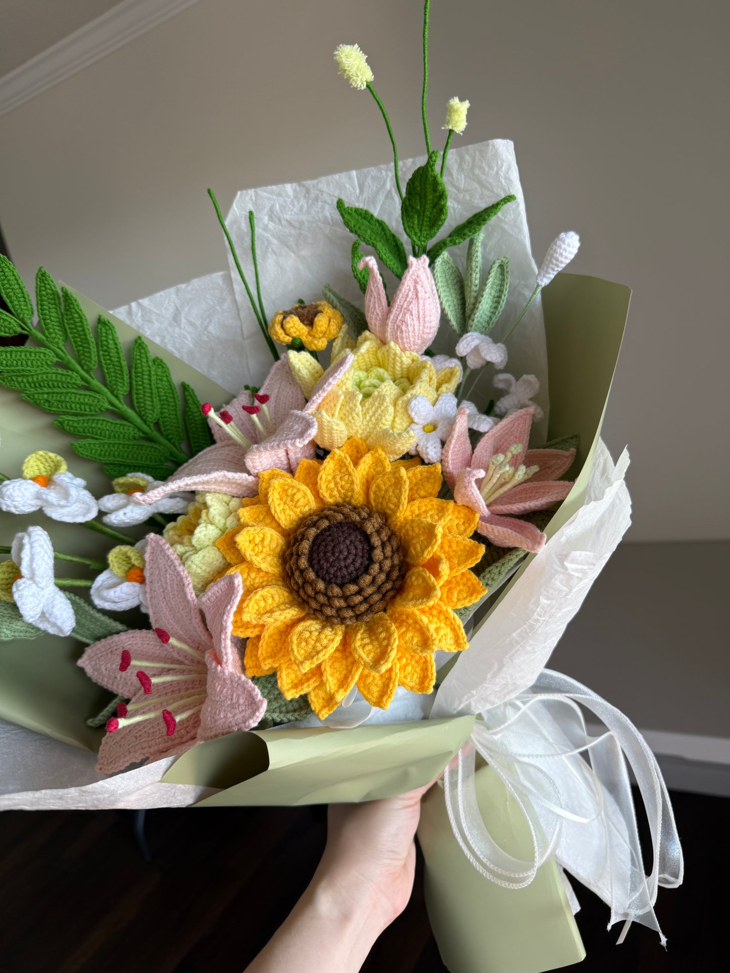 Bouquet of artificial flowers with a sunflower design held by a person.
