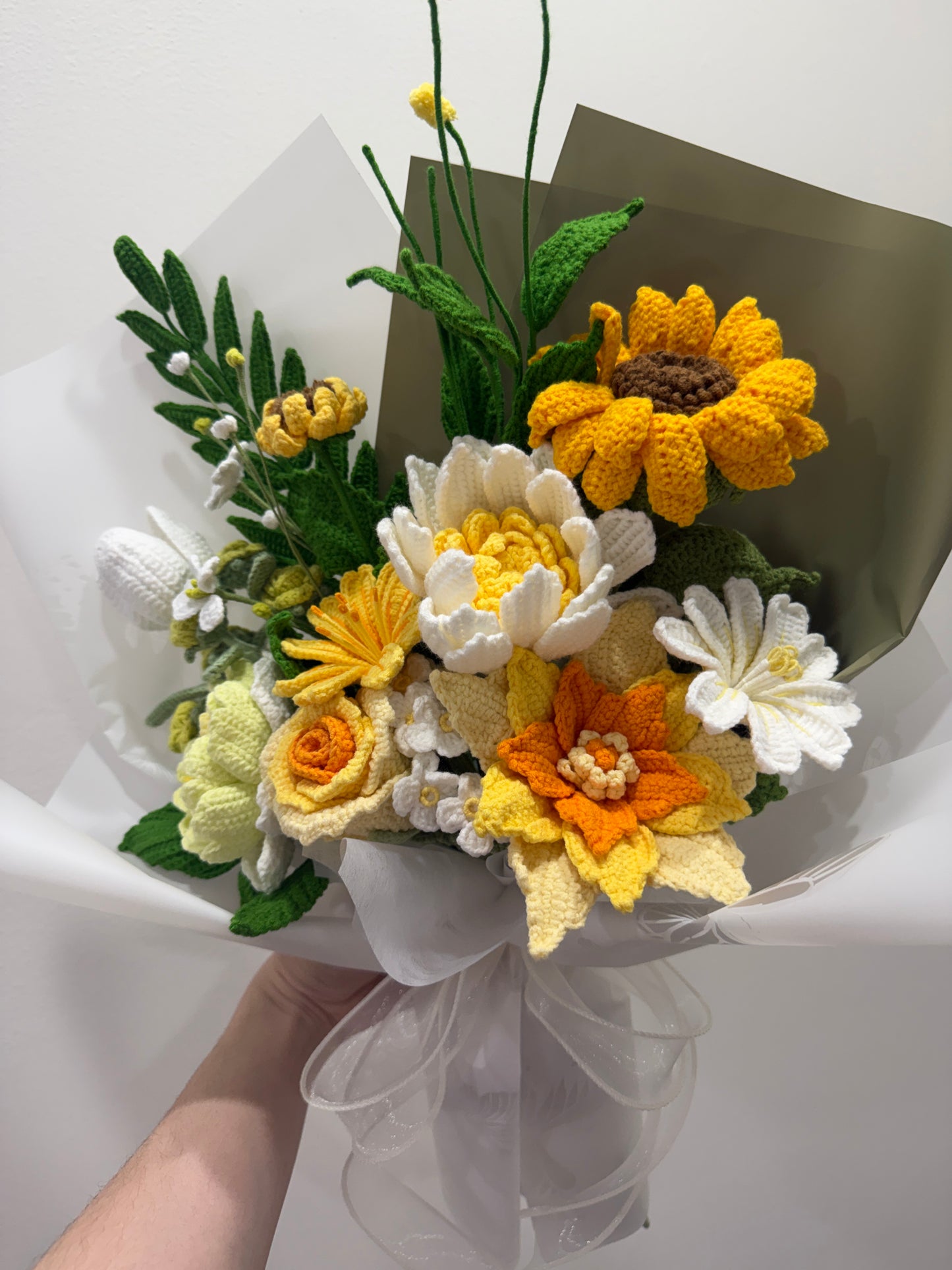 Knitted flower bouquet with yellow, white, and orange flowers on a white background
