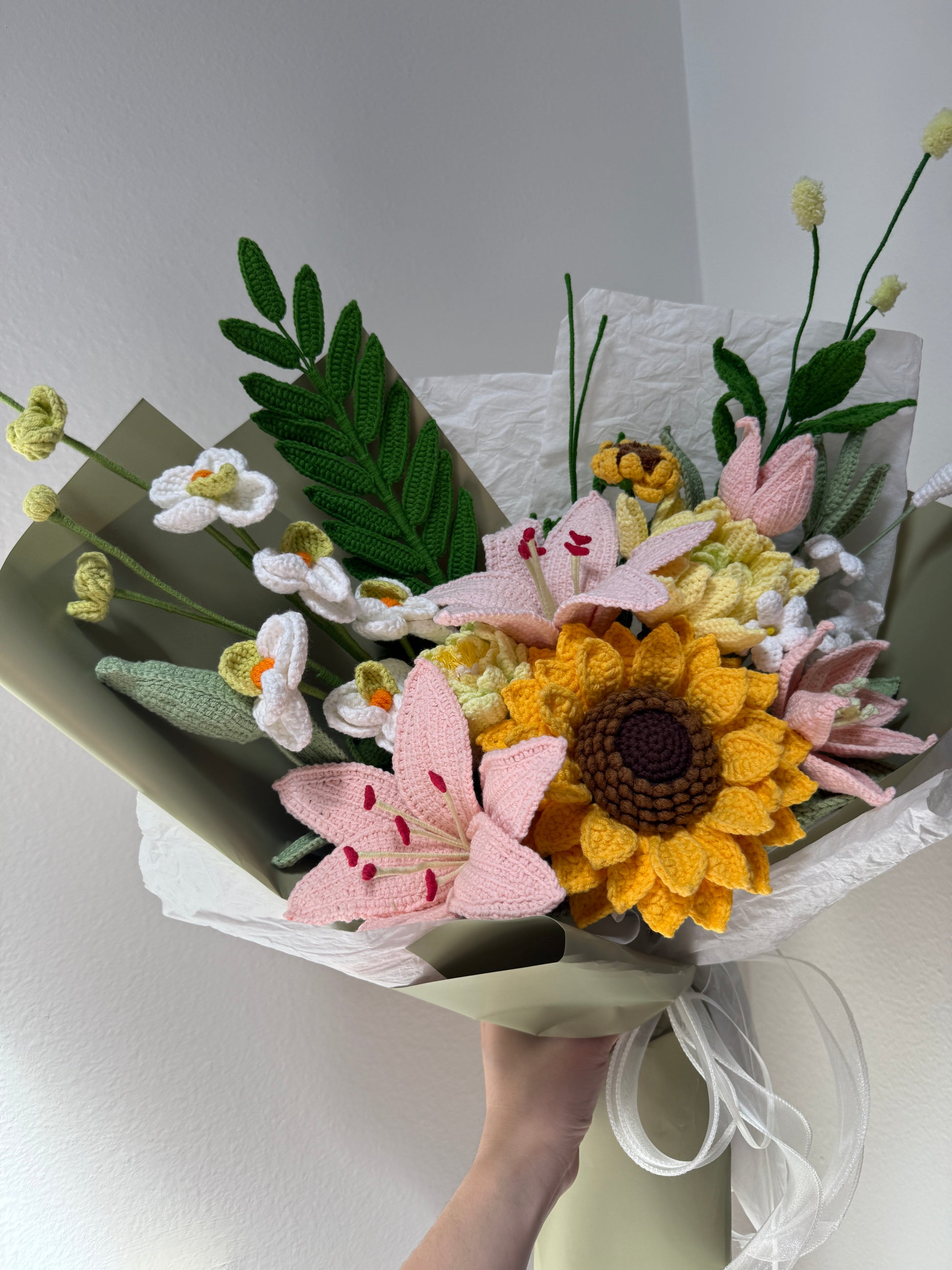 Bouquet of knitted flowers held by a hand on a light background