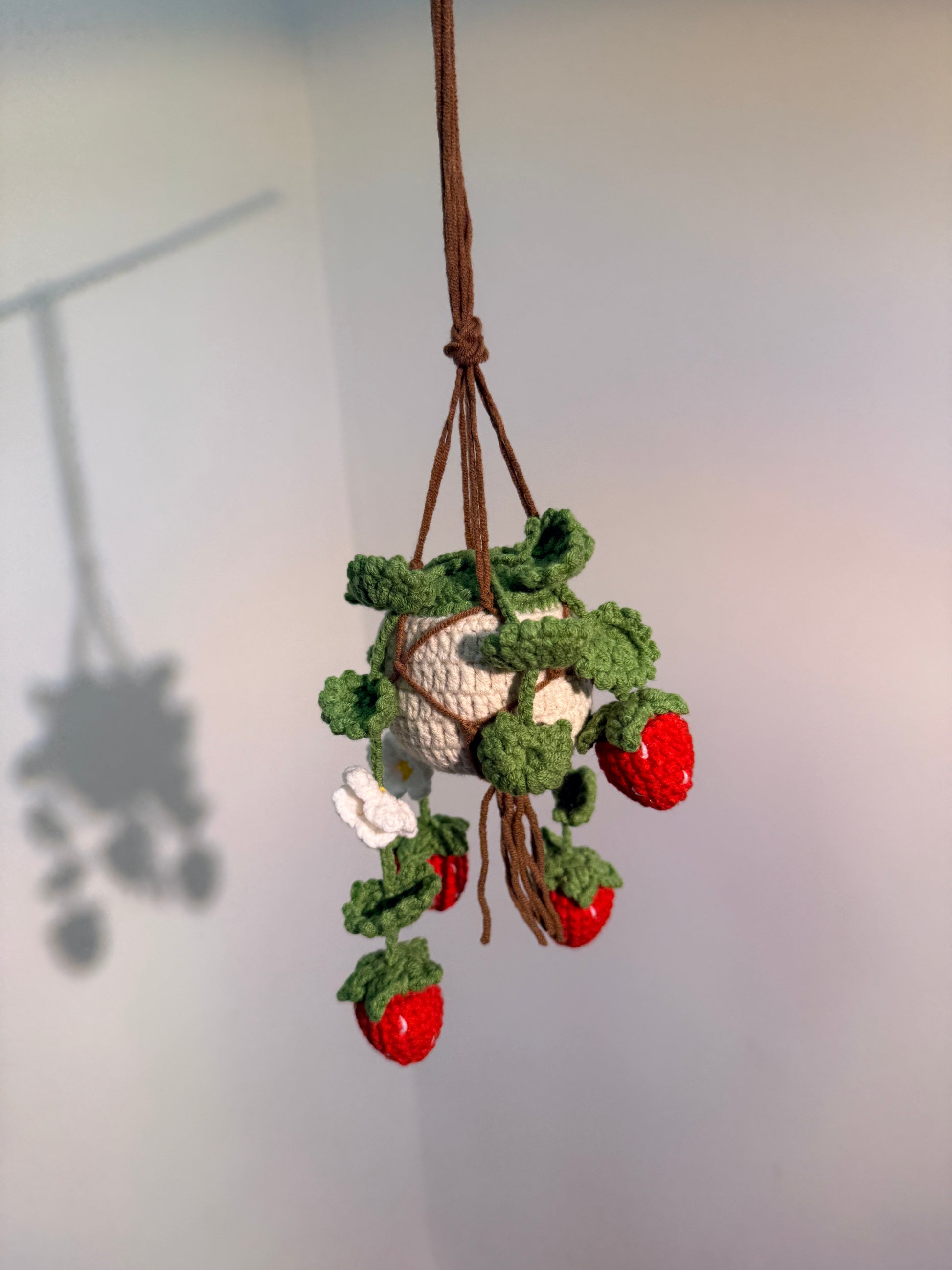 Crocheted strawberry branch with green leaves on a white background