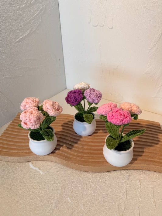 Decorative wall art with artificial flowers in white pots on a wooden board.