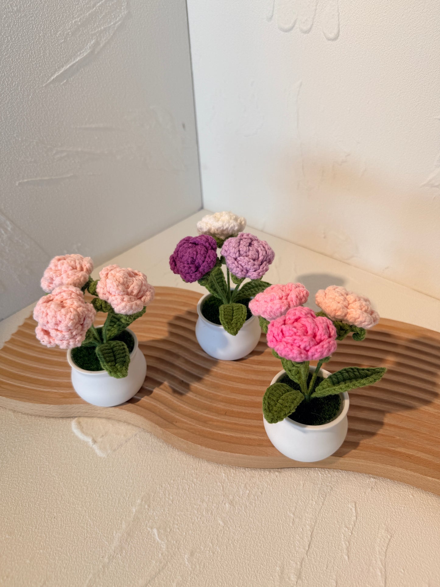 Small potted plants with pink and purple flowers on a wooden surface.